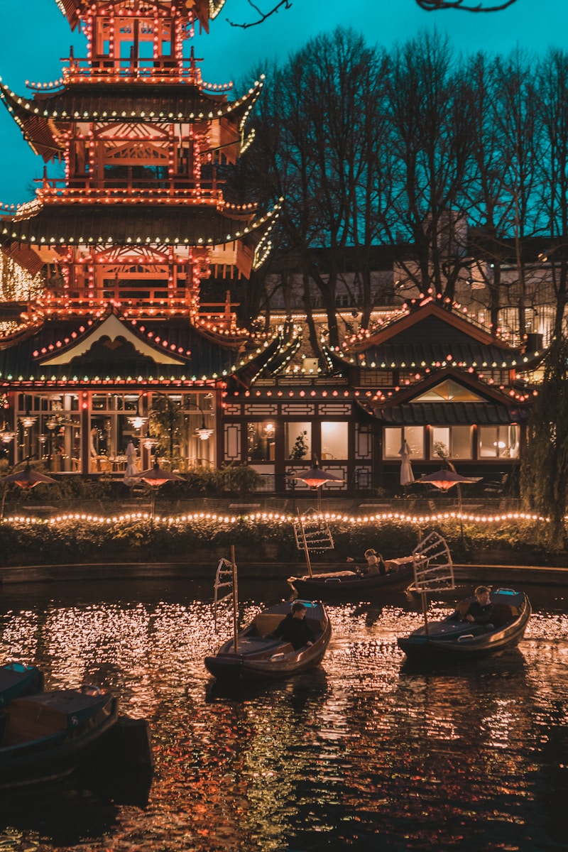 a chinese pagoda lit up at night with boats in the water